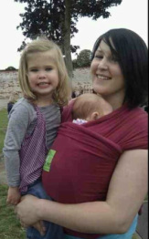 A mum carries her newborn in a stretchy Kari-me wrap, with her older daugher 