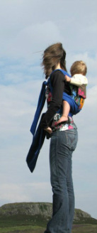 A babywearer with her toddler on her back out on a walk in Scotland