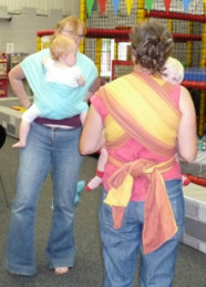 Two ladies share tips on wrapping their babies at a sling meet.