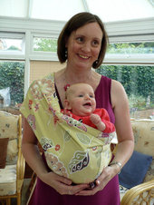 A mum carries her baby in a pouch at a formal event
