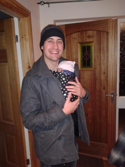 A dad and his baby in a stretchy wrap, bundled up to go for a walk