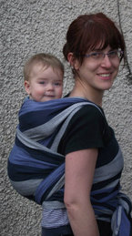 A mum carries her baby on her back in a Hoppediz woven wrap